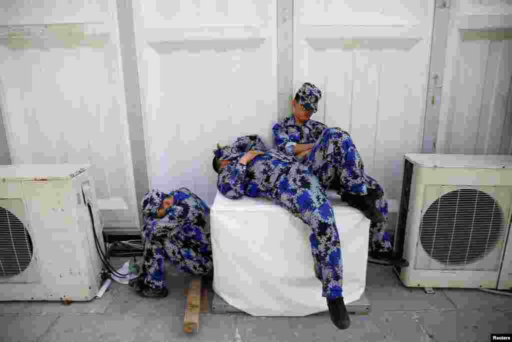 Security personnel take a nap behind one of the halls of Auto China 2016 auto show in Beijing.