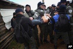 Israeli police arrest a settler in the West Bank outpost of Amona, Feb. 1, 2017.