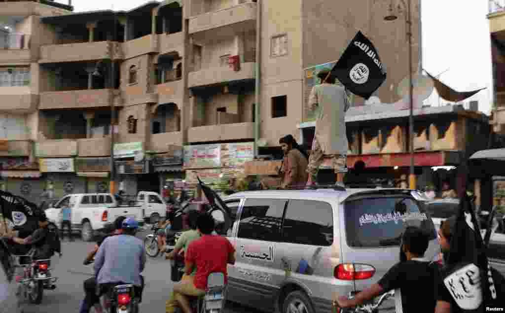 Members of the Islamic State in Iraq and the Levant wave ISIL flags as they drive around Raqqa, Iraq, June 29, 2014.