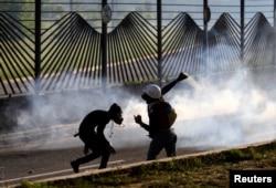 Opposition supporters throw stones into an air base while clashing with riot security forces during a rally against President Nicolas Maduro in Caracas, Venezuela, May 18, 2017.