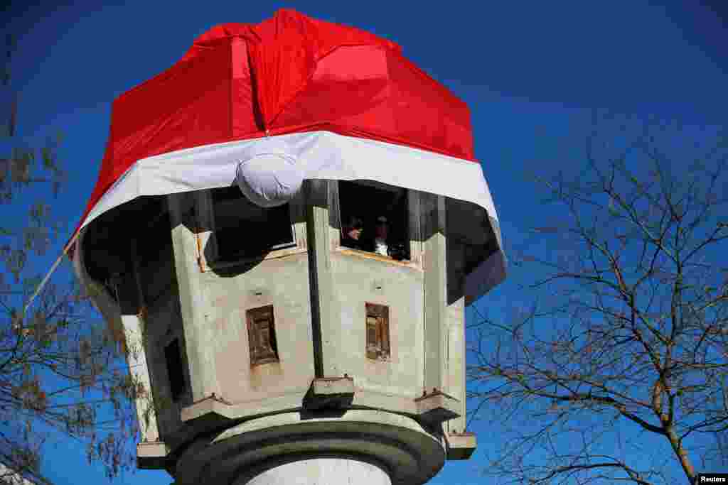 Tourists visit a former GDR border watchtower which is fitted with a Santa Claus hat near Potsdamer Platz square in Berlin, Germany.