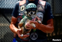 A man holds his dog, as participants gather in the parking lot of the Pentagon as thousands of military veterans and their supporters participate in the 31st annual Rolling Thunder motorcycle rally and Memorial Day weekend.