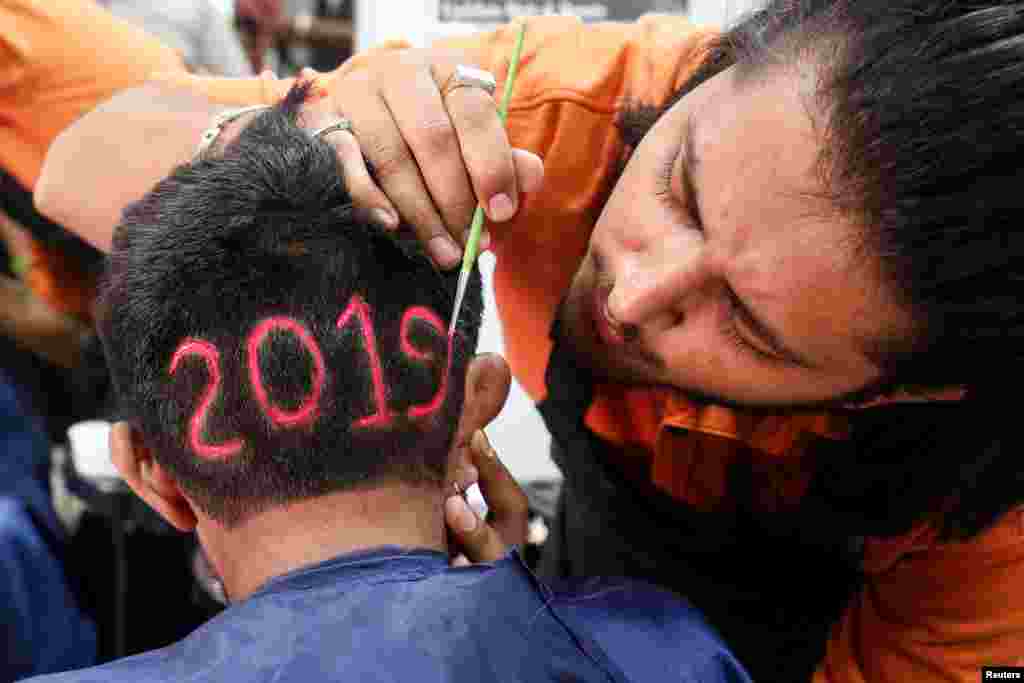A man applies color to a haircut with "2019", to welcome the new year at a barbershop in Ahmedabad, India.