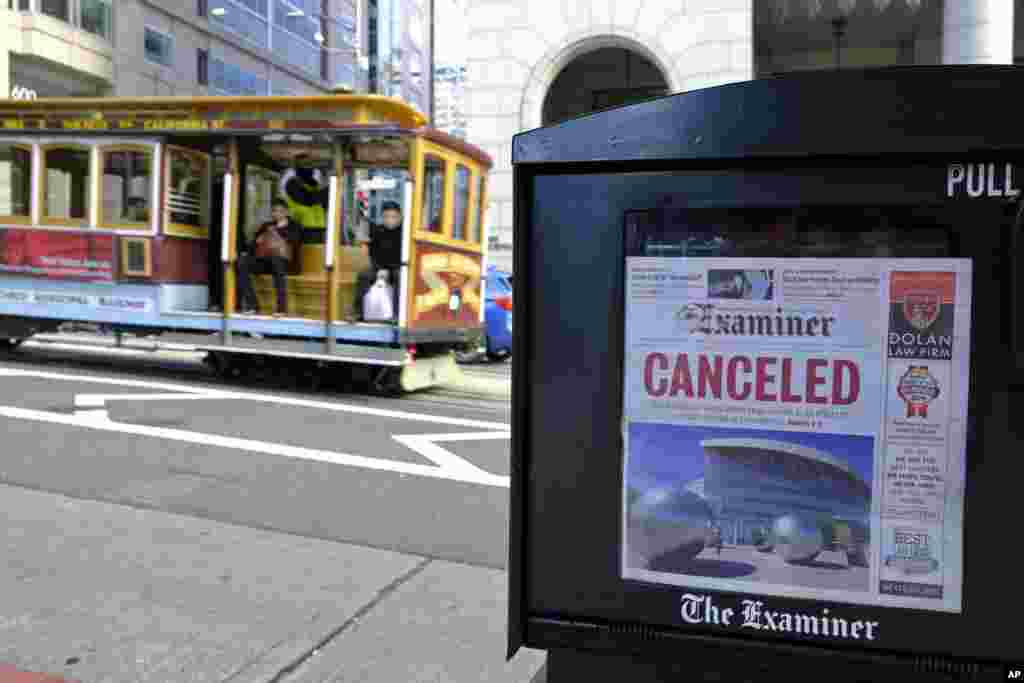 A newspaper headline announcing the closure of large events is seen as a cable car goes down California Street in San Francisco.