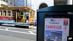 A newspaper headline announcing the closure of large events is displayed as a cable car goes down California Street in San Francisco. 