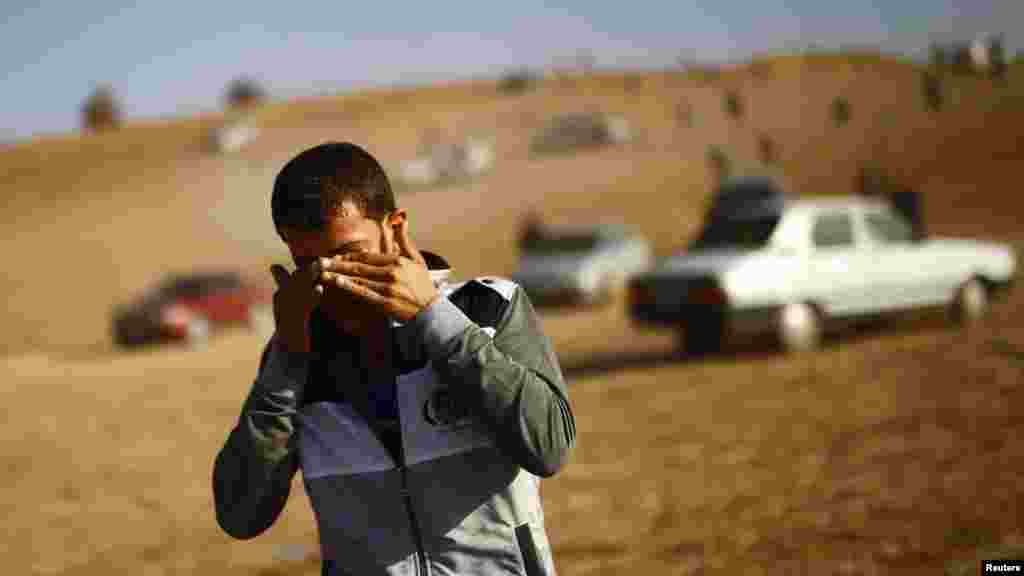 Một người đàn ông lau mắt sau khi quân đội Thổ Nhĩ Kỳ bắn hơi cay trong nỗ lực để giải tán những người quan sát ra khỏi một ngọn đồi gần cửa khẩu Mursitpinar trên biên giới Thổ Nhĩ Kỳ-Syria, ngày 26/10/2014. 