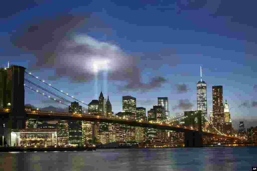 The Tribute in Light rises behind the Brooklyn Bridge and buildings adjacent to the World Trade Center complex, Sept. 10, 2014 in New York. 