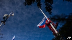 A member of a pro-Russian self-defense force takes down a Ukrainian Navy flag, left, as another raises the Russian flag at Ukrainian Navy headquarters in Sevastopol, Crimea, March 19, 2014.