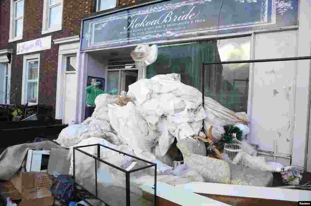 A man throws out flood-ruined stock from a wedding clothing business in Carlisle, northern England.