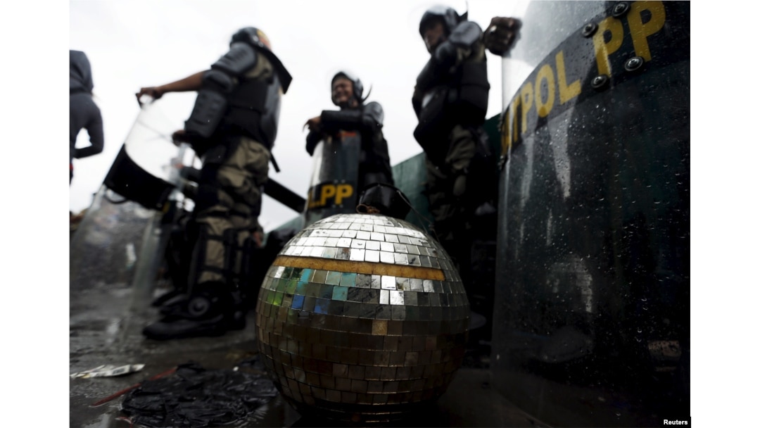 FILE - A disco ball rests near civil service police unit members as buildings are demolished at Kalijodo red light district in Jakarta, Indonesia, Feb. 29, 2016.
