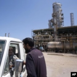 A Libyan worker chats with two rebels in a vehicle as they patrol an oil refinery controlled by anti Gadhafi forces on the western outskirt of Zawiya city, August 19, 2011