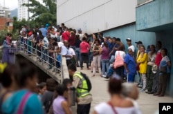 People wait outside a supermarket to buy government subsided food in Caracas, Venezuela, Nov. 18, 2016. As domestic production dries up in Venezuela, the state has given itself the role of importing nearly all the country's food.