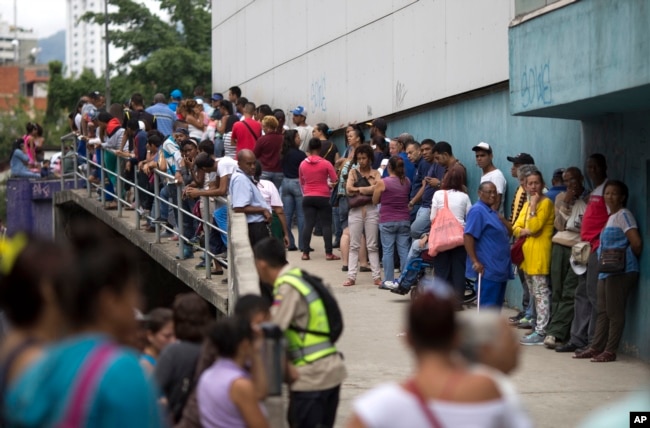 FILE - People wait outside a supermarket to buy government subsided food in Caracas, Venezuela, Nov. 18, 2016.