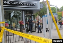 Police officers enter a coffee shop damaged by gunfire while investigating a mass shooting on Danforth Avenue in Toronto, Canada, July 23, 2018.