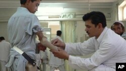 An Afghan technician helps a young amputee adjust his prosthetic arm at one of the International Committee of the Red Cross (ICRC) hospitals for war victims and the disabled in Jalalabad on June 26, 2012.