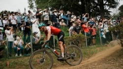 Fans watch from a hillside as Nino Schurter of Switzerland competes during the men's cross country mountain bike competition at the 2020 Summer Olympics, Monday, July 26, 2021, in Izu, Japan. (AP Photo/Thibault Camus)