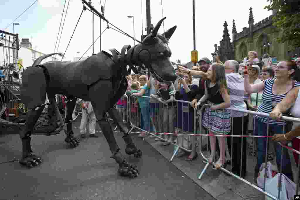 A giant dog is steered through the center of Liverpool, England as she and two other giants, a girl, left, and a grandmother parade for three days telling the story of the city's involvement in World War I.