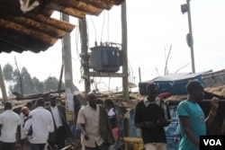 People walk by a large transformer in Kibera, Kenya. Cartels provide electricity to residents at a cost as low as $3 by tapping into such transformers. (R. Ombuor/VOA)