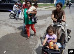 A couple of Honduran migrant mothers carry their children as they continue on their trek to the United States, in Teculutan, Guatemala, Oct. 17, 2018.