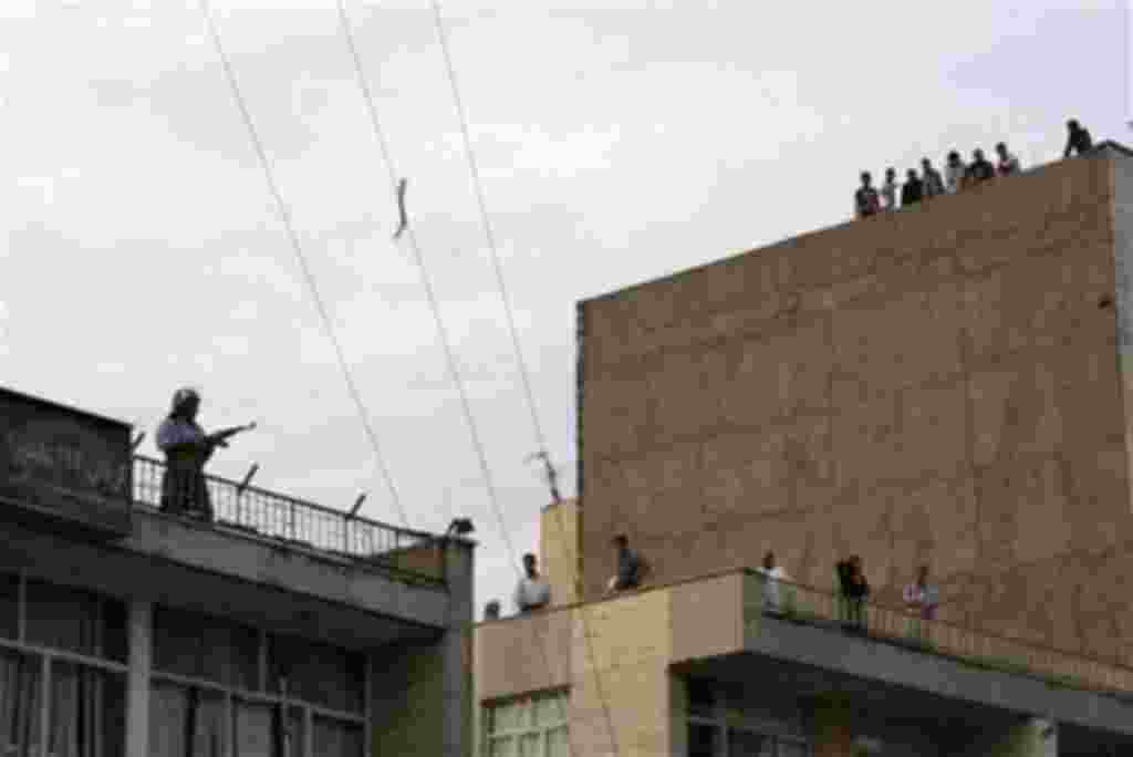 A member of a pro-government militia, left, stands guard on a rooftop of their base as demonstrators approach, near a rally supporting leading opposition presidential candidate Mir Hossein Mousavi in Tehran, Iran, Monday, June 15, 2009. Shots were fired