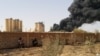 FILE - Members of forces loyal to Libya's eastern government sit near a factory during clashes with the Shura Council of Libyan Revolutionaries, an alliance of former anti-Gaddafi rebels who have joined forces with Islamist group Ansar al-Sharia.