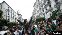 FILE - Demonstrators hold flags and banners during peaceful anti-government protests in Algiers, Algeria, May 3, 2019.