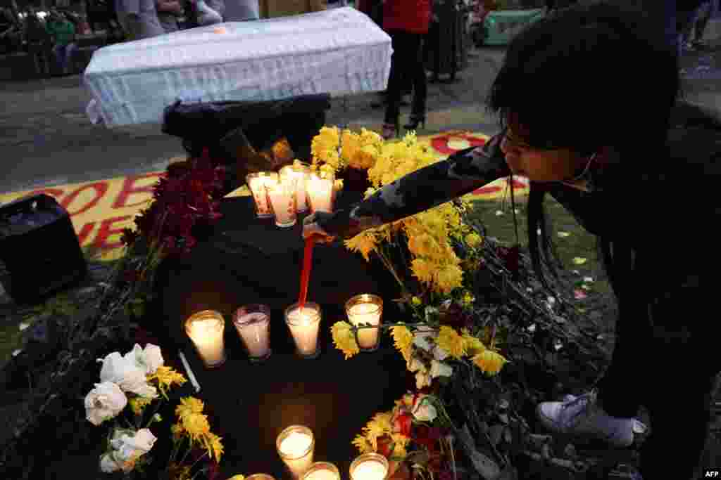 Niña enciende una vela en memoria de las víctimas del COVID-19 durante una protesta contra el Bicentenario de la Independencia de Guatemala.