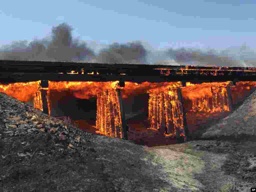 In this photo provided by Kiowa County Sheriff Casey Sheridan, a railroad trestle burns near the tiny town of Haswell, Colorado, June 22, 2016.