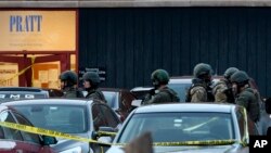 Law enforcement officers gather outside the Henry Pratt Co. manufacturing plant, Feb. 15, 2019, in Aurora, Ill., where a gunman killed five co-workers and injured several police officers.
