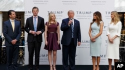 FILE - Then-candidate Donald Trump, accompanied by his family, speaks during the grand opening of the Trump International Hotel-Old Post Office, Washington, Oct. 26, 2016. Experts on government ethics are warning President-elect Trump that he’ll never shake suspicions of a clash between his private interests and the public good if he doesn’t sell off his vast holdings.