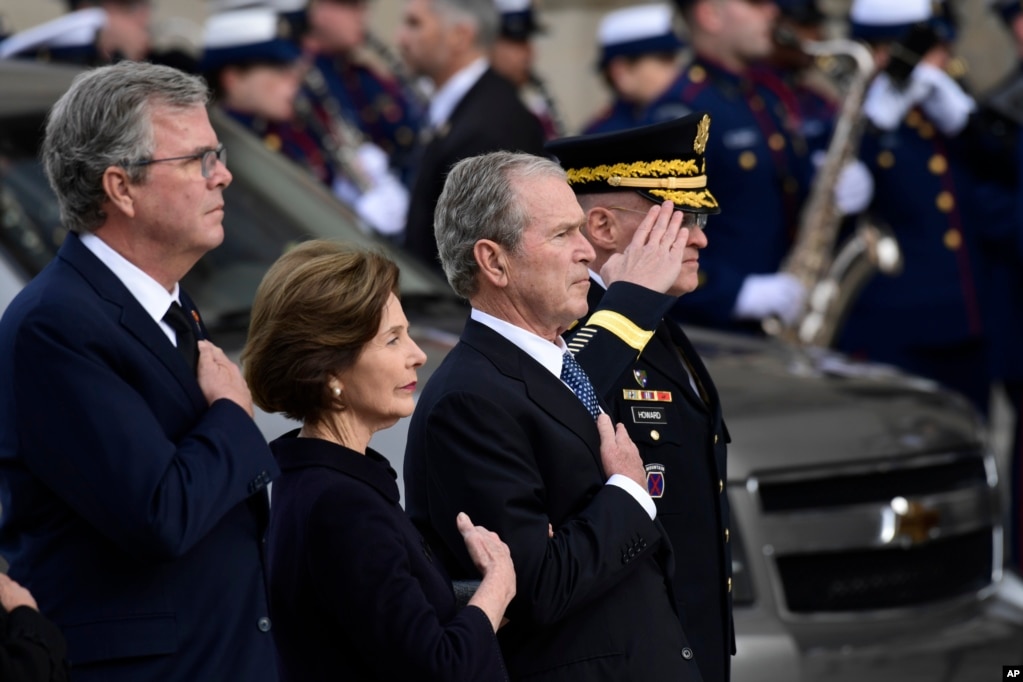 President George W. Bush, his wife Laura Bush and brother Jeb Bush watch as the casket of former President George H.W. Bush arrives at the National Cathedral, Dec. 5, 2018, in Washington, for a State Funeral.