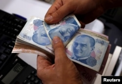 FILE - A money changer counts Turkish lira notes at a currency exchange office in Istanbul, Aug. 2, 2018. The lira has taken a beating since U.S. sanctions were applied in the case of a detained pastor, Andrew Brunson.