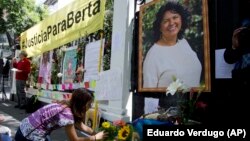 A woman places flowers on an altar set up in honor of Berta Caceres during a demonstration outside Honduras' embassy in Mexico City.