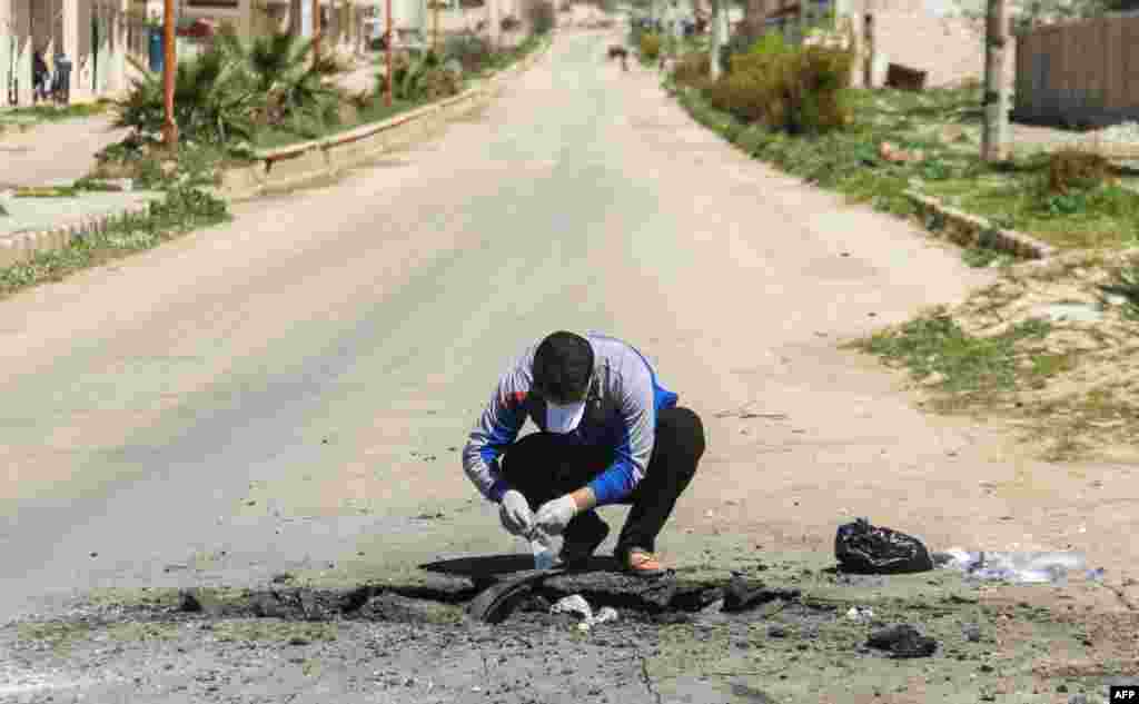 A Syrian man collects samples from the site of a suspected toxic gas attack in Khan Sheikhun, in Syria&rsquo;s northwestern Idlib province, April 5, 2017.