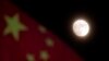 FILE - The moon is seen near a Chinese national flag in Beijing, Dec. 15, 2013. NASA says the U.S. can one day cooperate with China in its space exploration.
