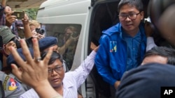 Reuters journalist Thet Oo Maung Maung, known as Wa Lone, exits a police van while his wife Pan Ei Mon waves upon his arrival at the township court for an appearance Wednesday, Dec. 27, 2017, outside Yangon, Myanmar. The court has extended the detention of the two Reuters journalists, Wa Lone and his colleague Kyaw Soe Oo, and set their trial date for Jan. 10 on charges of violating state secrets. (AP Photo/Thein Zaw)