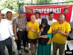 Polisi bersama ketiga tersangka (baju kuning) terbakarnya pabrik rumahan korek api gas di Langkat, Sumatera Utara, Indramawan (kiri), Lismawarni, dan Burhan, Senin (24/6). (VOA/Anugrah Andriansyah)