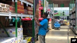 FILE: A man takes images of goods in a shop to share before buying them in Harare. Hyperinflation is changing prices quickly in the southern African nation.