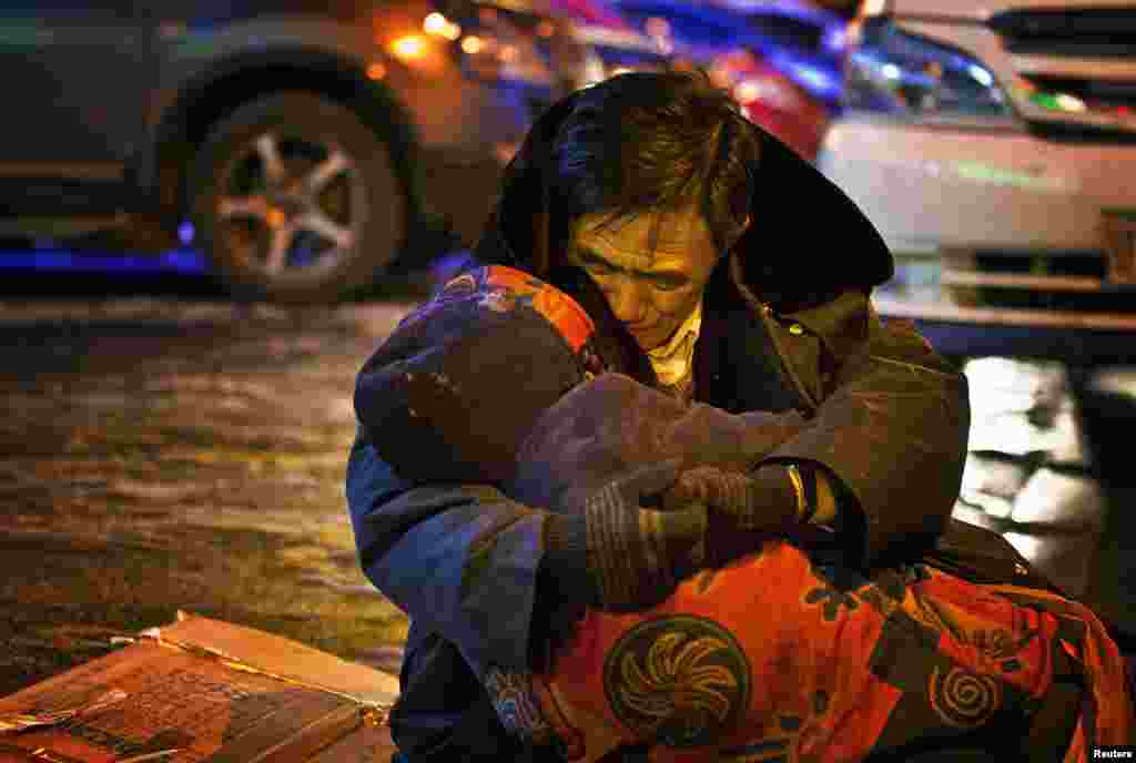 A man, whose surname is He, cuddles the body of his dead wife during a sub-zero evening in Shenyang, Liaoning province, China, Dec. 17, 2014. The man sat by the roadside while holding his wife's body for almost two hours until his son came and persuaded him to bring the body home, according to local media. She collapsed in a street and died of heart failure after buying medicine from a pharmacy.