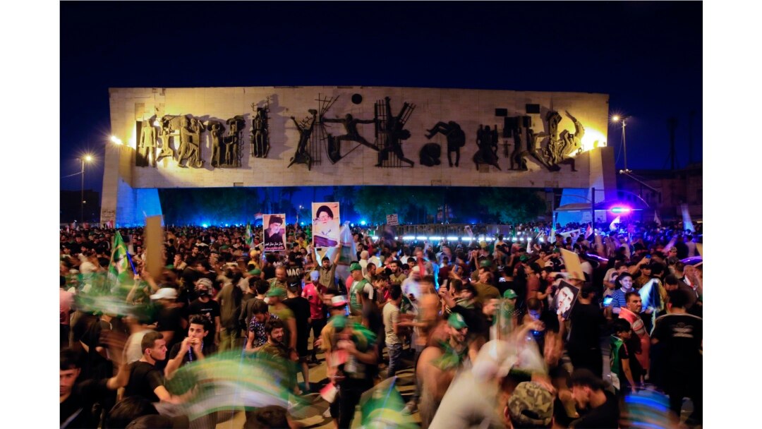 Pengikut ulama Syiah Muqtada al-Sadr merayakan kemenangannya dengan memegang poster, setelah pengumuman hasil pemilihan parlemen di Tahrir Square, Baghdad, Irak, Senin, 11 Oktober 2021. (Foto: AP)