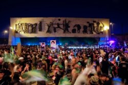 Pengikut ulama Syiah Muqtada al-Sadr merayakan kemenangannya dengan memegang poster, setelah pengumuman hasil pemilihan parlemen di Tahrir Square, Baghdad, Irak, Senin, 11 Oktober 2021. (Foto: AP)