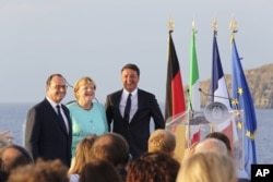 FILE - Italian Premier Matteo Renzi, right, French President Francois Hollande, left, and German Chancellor Angela Merkel stand on the deck of an Italian aircraft carrier off of Italy, Aug. 22, 2016. The leaders of Italy, France and Germany are watching t