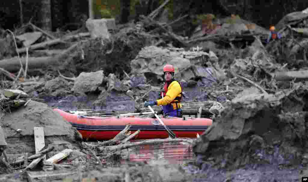 A searcher uses a small boat to look through debris from a deadly mudslide in Oso, Washington, USA, Mar. 25, 2014. At least 14 people were killed in the 1-square-mile slide that hit in a rural area about 55 miles northeast of Seattle on Mar. 23. Several people also were critically injured, and homes were destroyed.