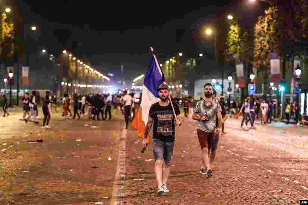 Para pengunjung berjalan setelah merayakan hasil laga final Piala Dunia 2018 antara Perancis dan Kroasia, di Champs-Elysees di Paris, 15 Juli 2018.