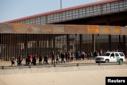 FILE - Migrants are escorted by U.S. Customs and Border Protection officials after crossing illegally into the United States to request asylum, in El Paso, Texas, in this picture taken from Ciudad Juarez, Mexico, April 3, 2019.