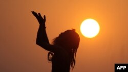 An Indian sadhu - holy man - performs yoga at sunrise at the Dashashwamedh Ghat in Varanasi on October 27, 2016. 