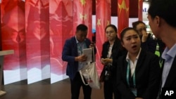 Attendees stand near a display of the Chinese flag during the China International Import Expo in Shanghai, Nov. 6, 2018.