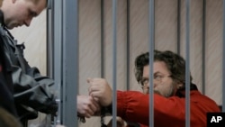 Полицейский снимает наручники с активиста Гринпис Романа Дольгова, в зале суда. Мурманск, Росси, 26 сентября 2013г.