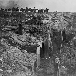 An abandoned British trench captured by the Germans. German soldiers are on horseback in the background.