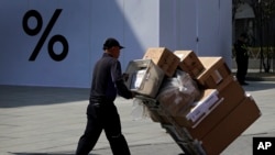 一名中國工人2019年4月4日用推車把貨物送進北京一家商場。
